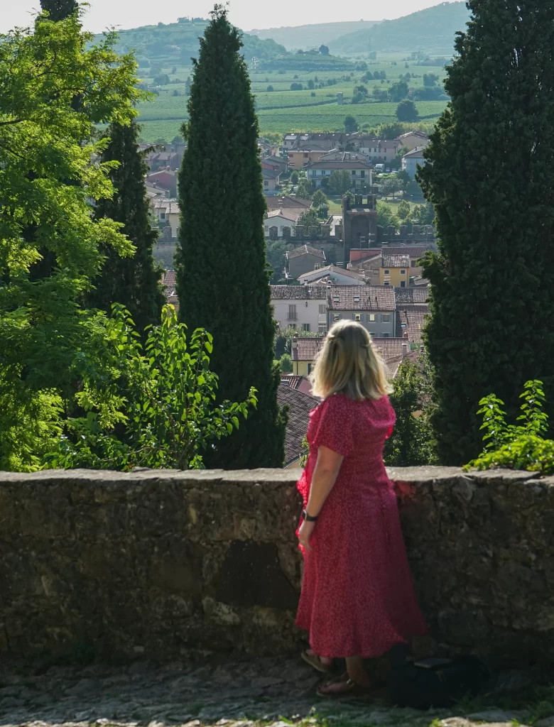 Woman in red dress looking out over rooftops of italian town