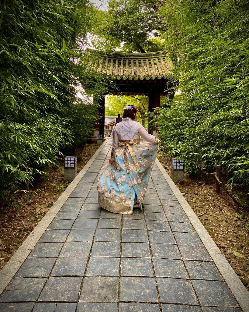 Woman in Hanbok holding her blue skirt up to the side in a pose