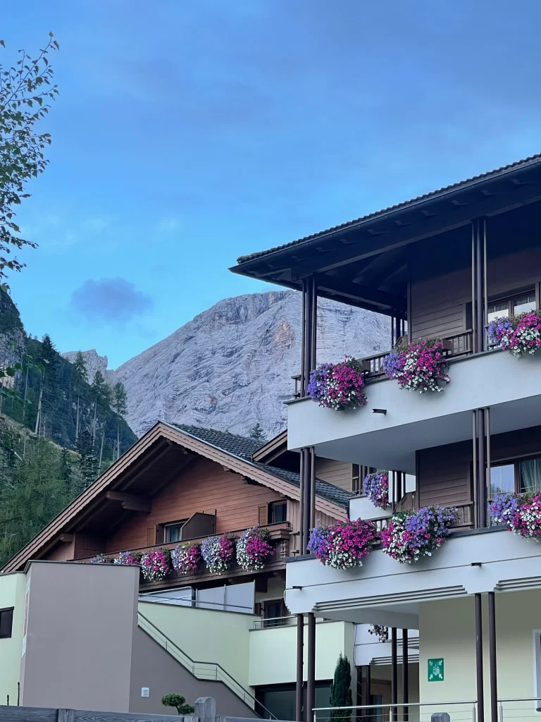 Hotel Trenker in the Lago Di Braies Valley. It's balconies have flowers hanging off of them with a wooden awning above. 
