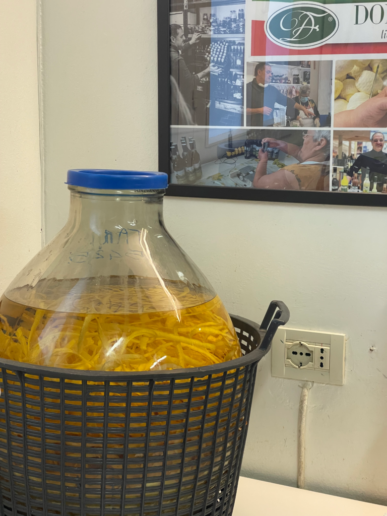 a demi jon with orange peels sits in the corner of a room at Donna Frida