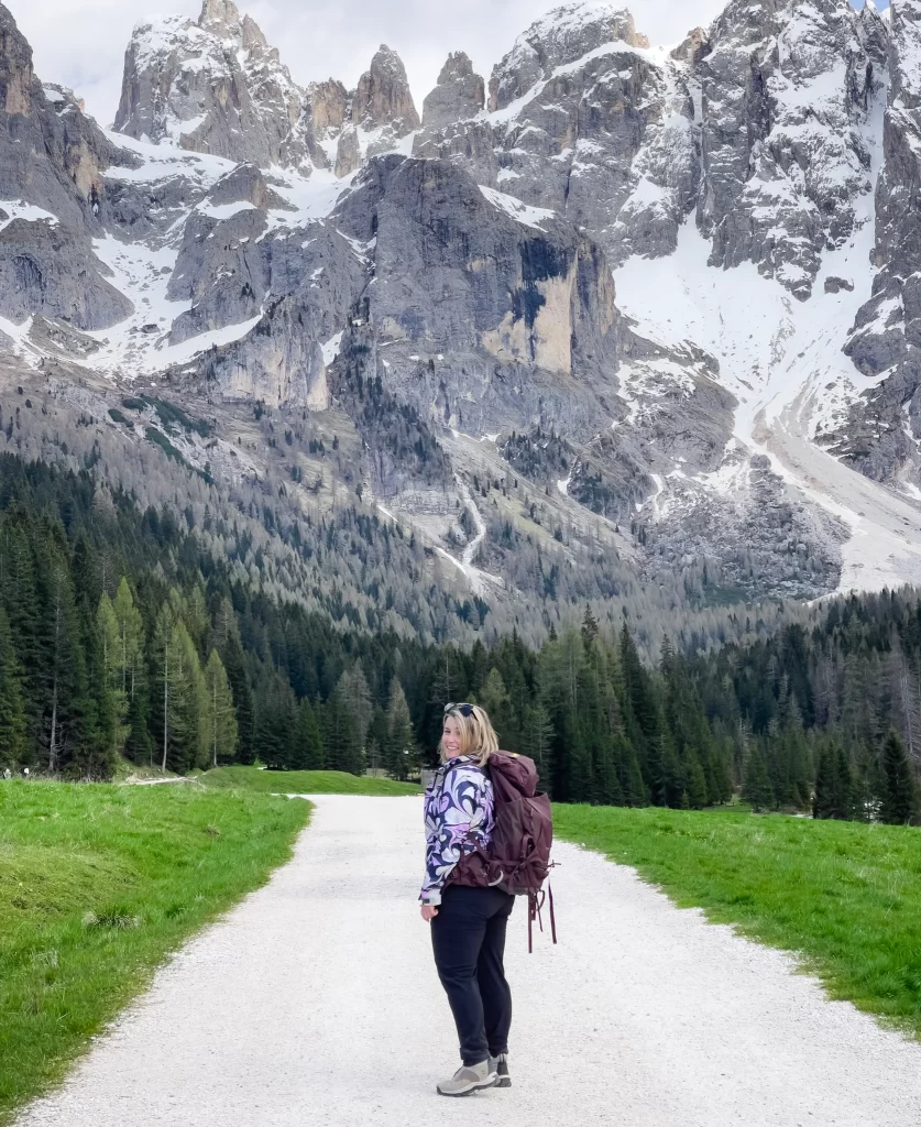 A woman wearing hiking boots and a backpack on a white rock path with a mountain backdrop