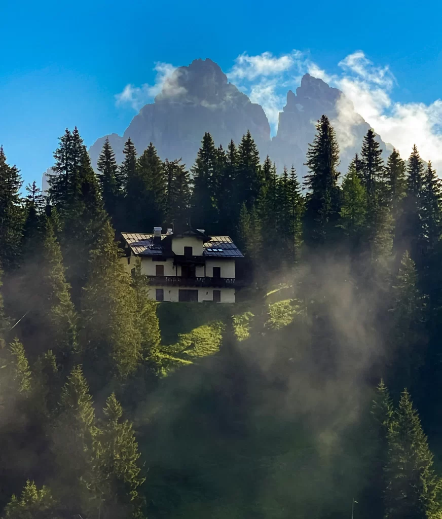 Lago di Misurina is the perfect first timers base to stay at. A Cabin rises through the alpine trees with mountain peaks behind them