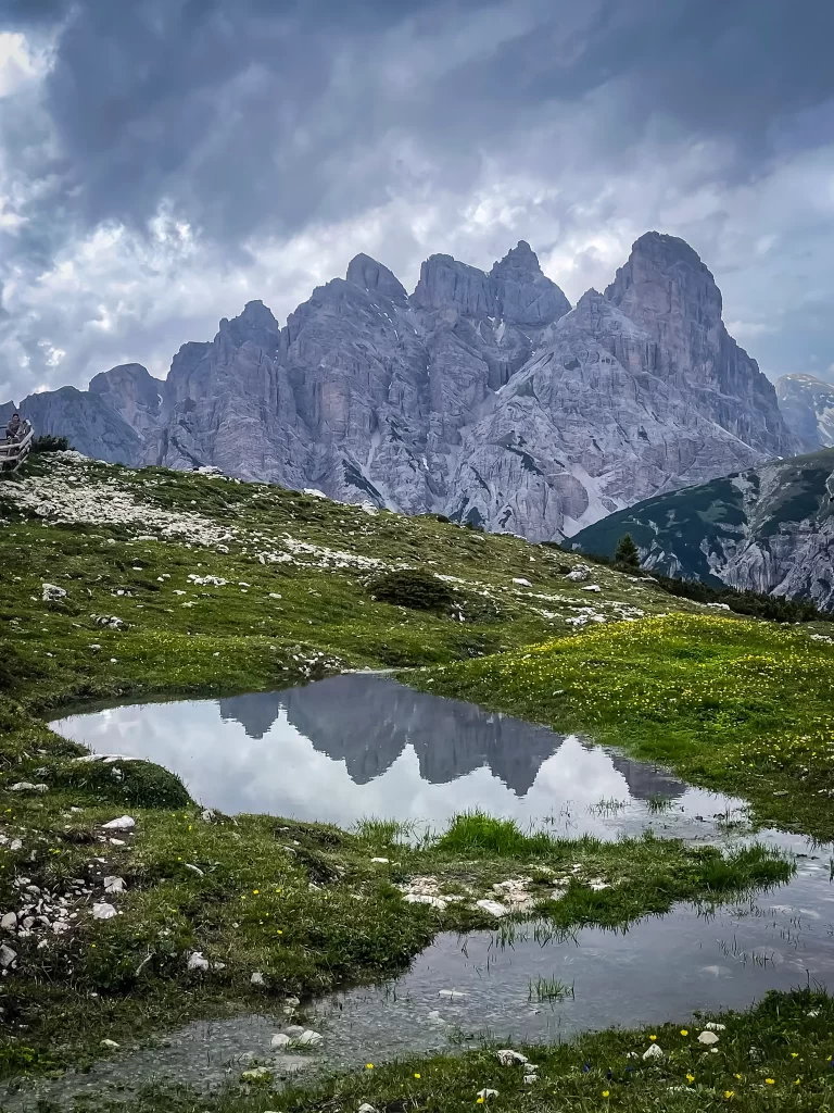 Small water source area by Malga Alm with mountain peaks reflecting in the background