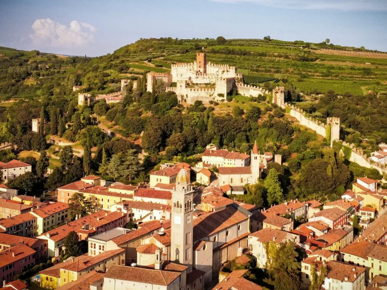 Castle with medieval town rising above and greenery behind the castle of soave, italy