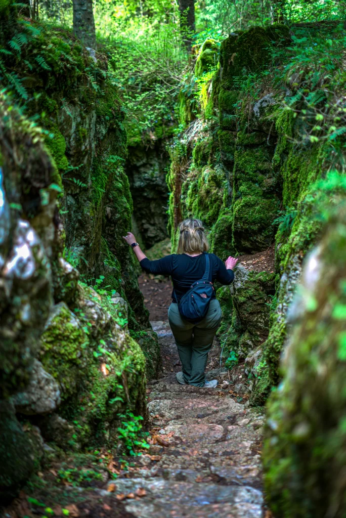 woman in a black shirt with a black backpack walking down the Forra del Lupo