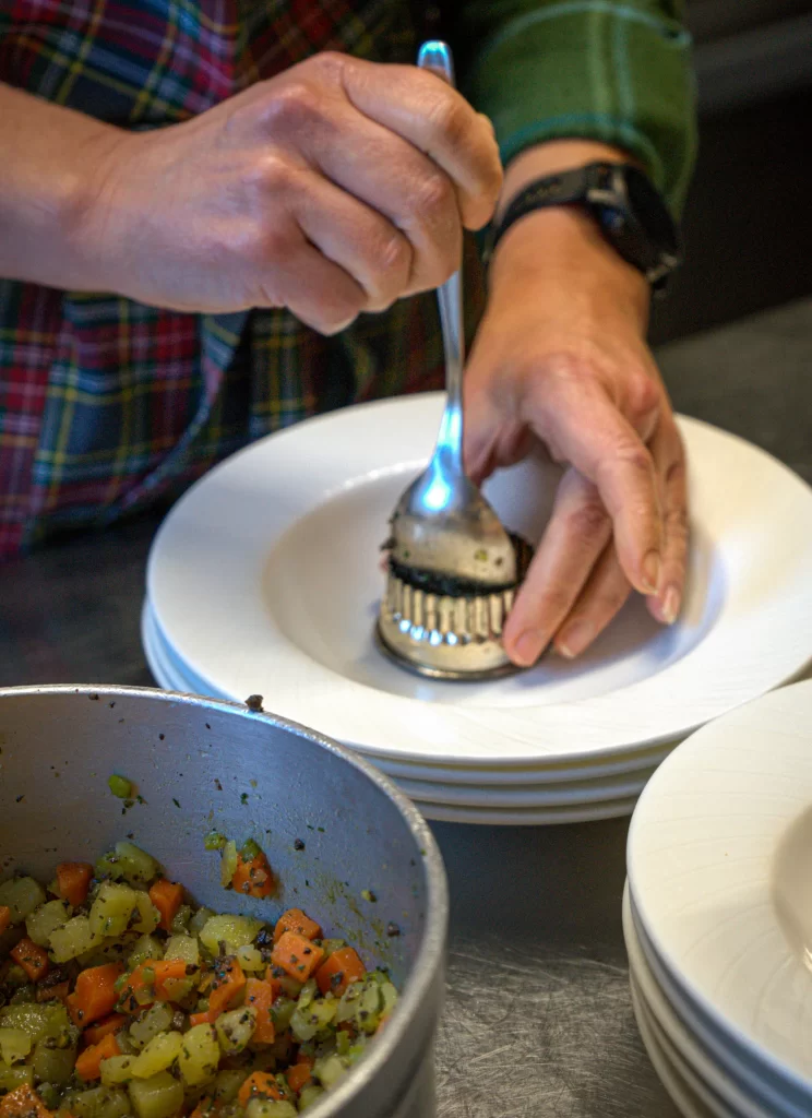 Hands placing a mold with food into a bowl to prep for eating at Trattoria All'Angelo