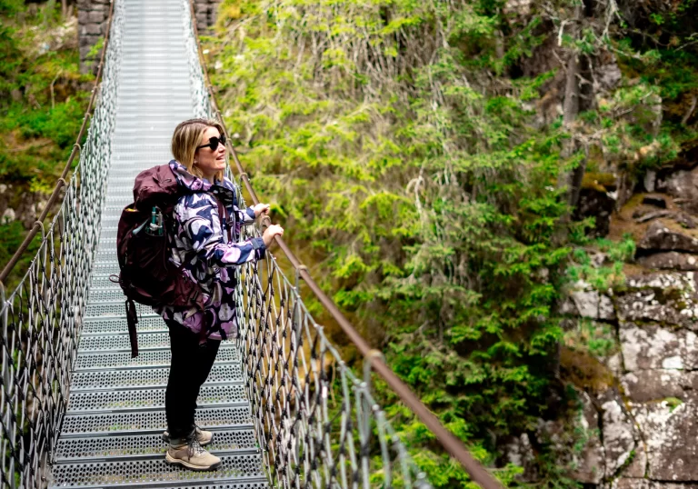 Woman on Bridge with Hiking boots and a backpack looking at waterfall on the Sentiero Marcio