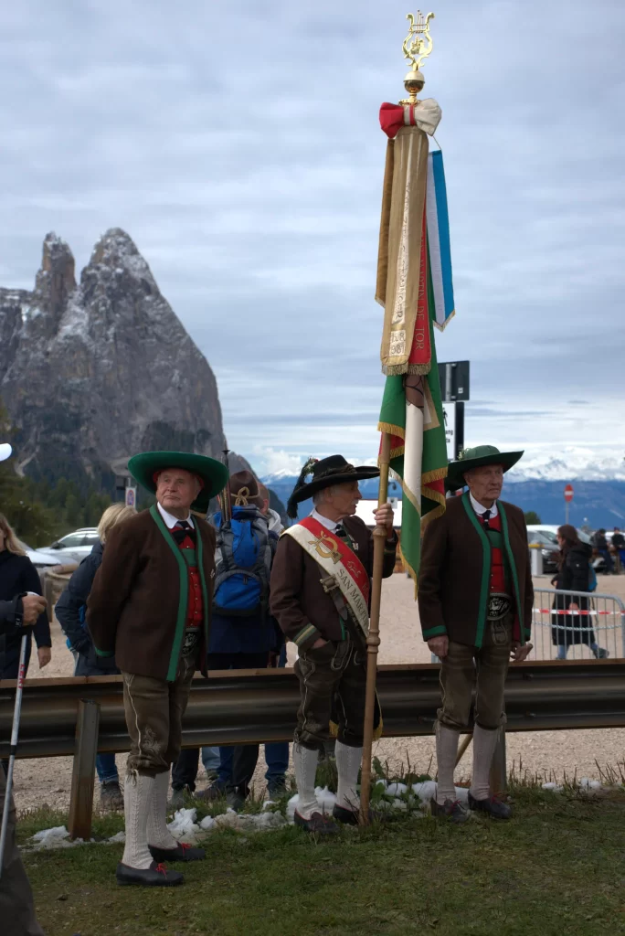 Three men who are apart of the town council in Compatsch wearing traditional Ladin outfits with wide brim hats, long socks and jackets