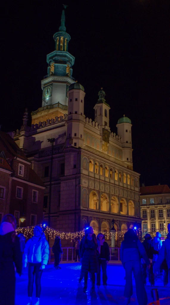 People Ice Skating illuminated in blue light against the Ratusz in Poznan