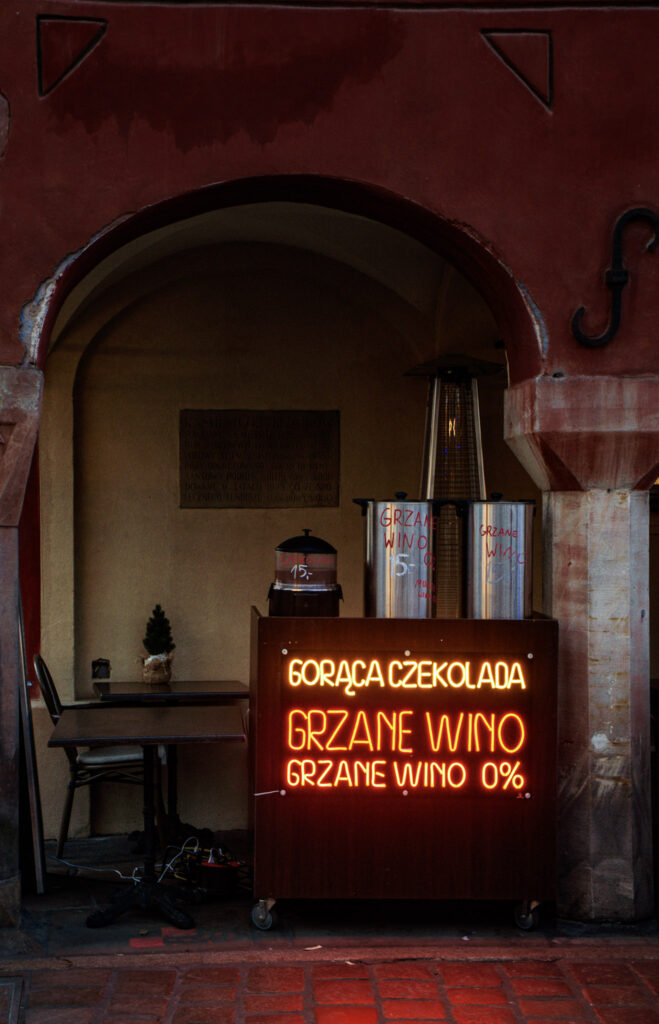A Mulled wine cart near the Ratusz of Poznan that is illuminated in red that says " GRAZNIEC WINO!"