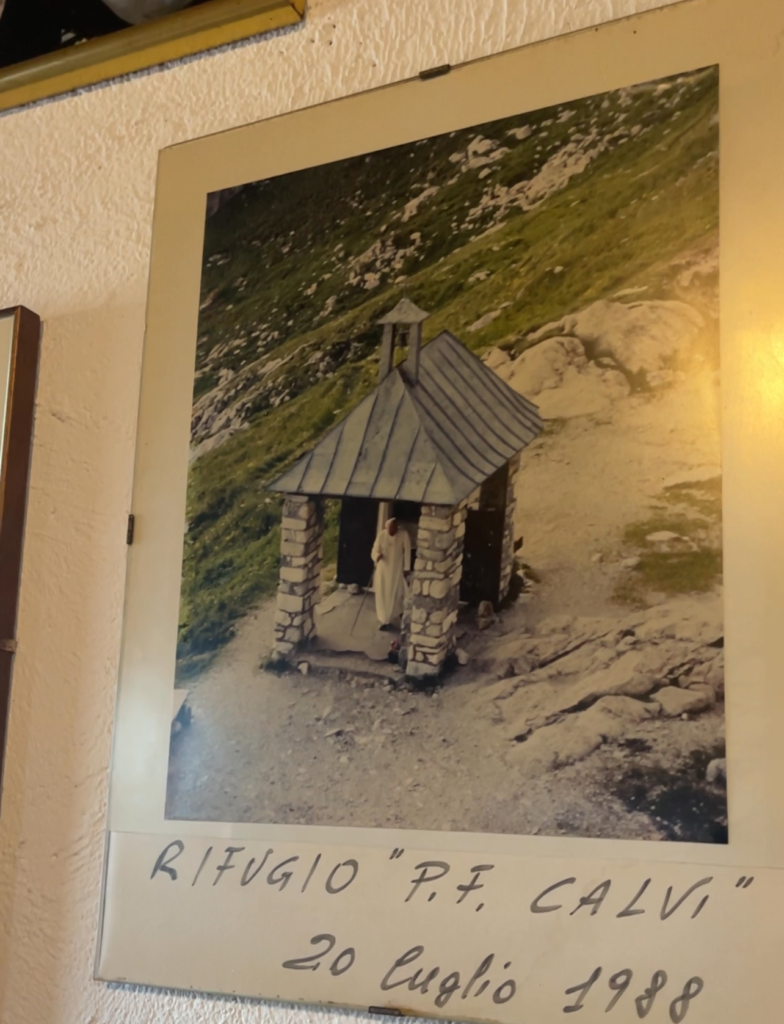 a Picture hanging in the rifugio calvi of pope john paul ringing bell outside of rifugio calvi