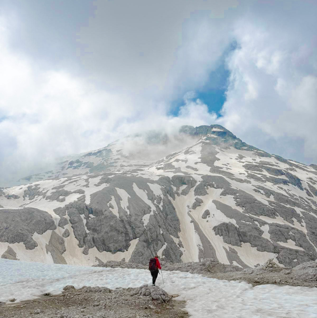 person in hiking gear hiking the pale di san martino in the snow with cloud cover