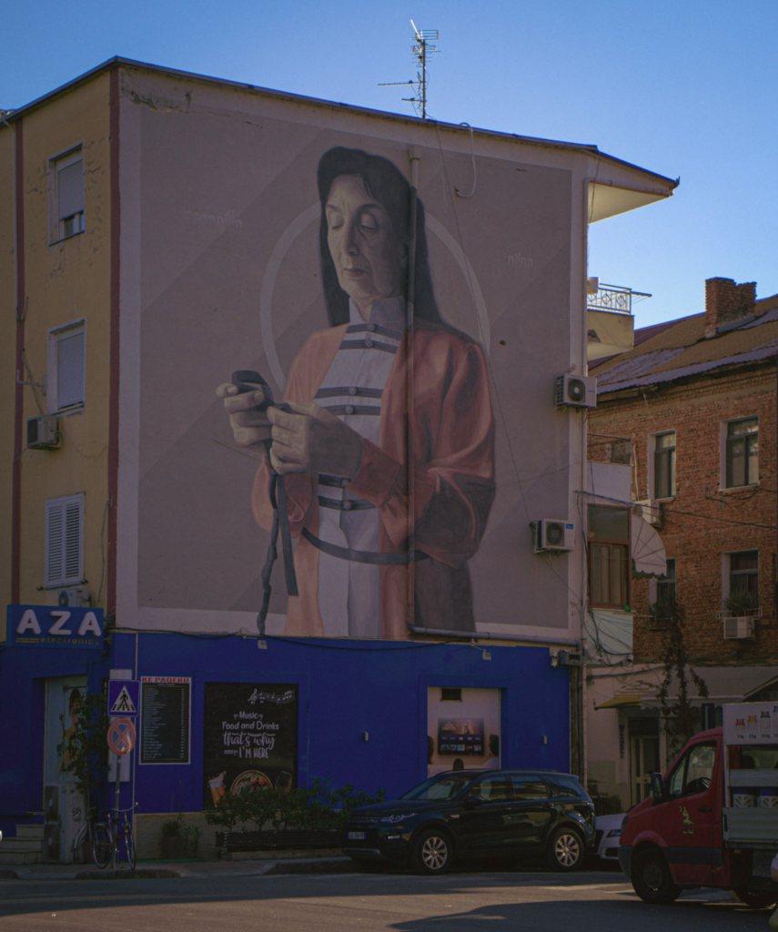 colorful street art on a building in Tirana Albania of a woman who appears to be a nun holding rosary