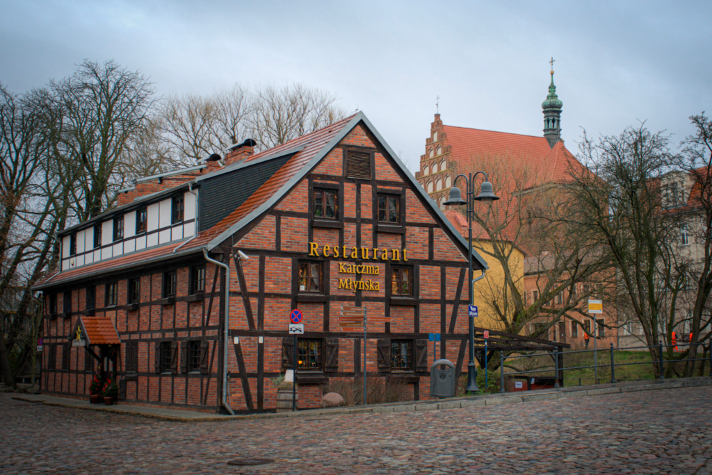 an old mill house with cobble stoned streets in front of it in Bydgoszcz
