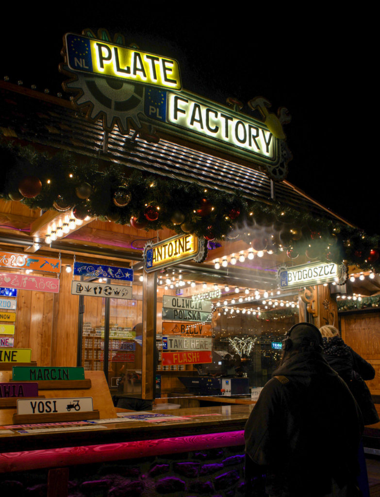 License Plate vendor at the bydgoszcz christmas market. Colorful license plates on display as a patron gets one made at the Bydgoszcz Christmas Market