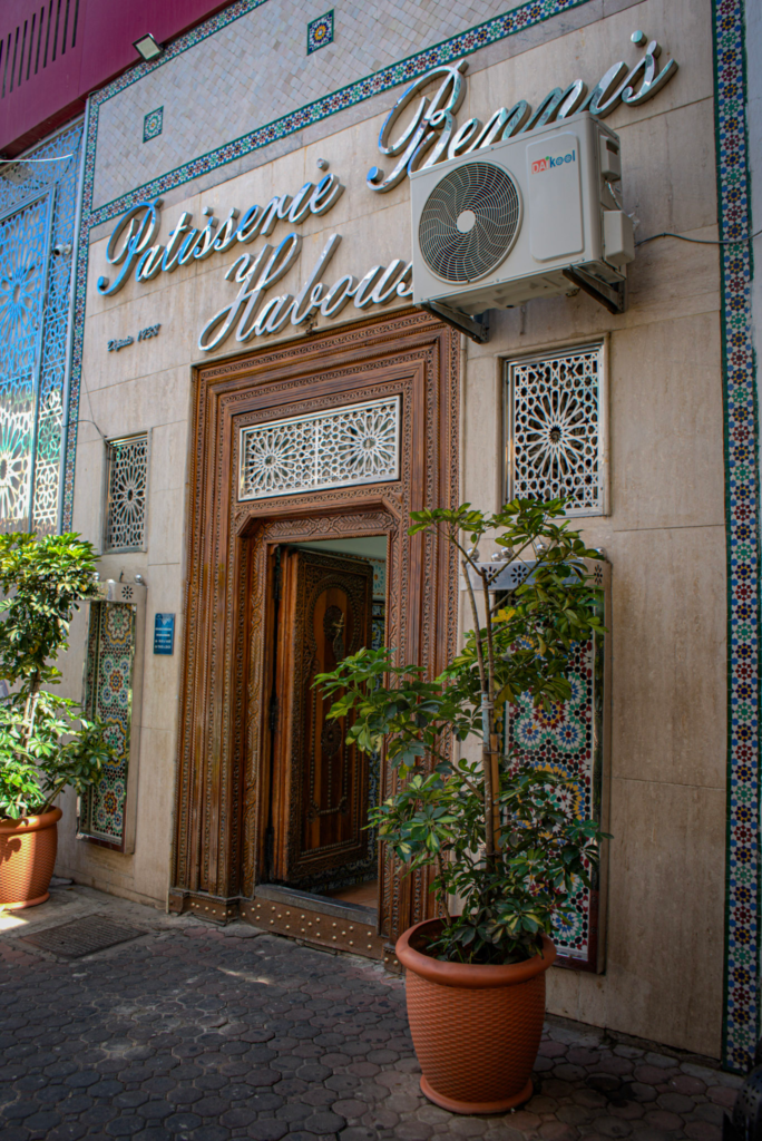 Front facade of Pâtisserie Bennis Habous in Casablanca Morocco covered in plants and the door is open
