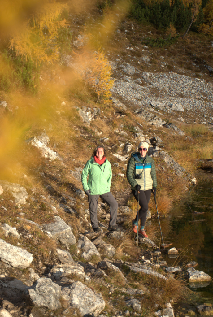 Two Female Hikers Wave at the Camera at Lago Federa in the morning light