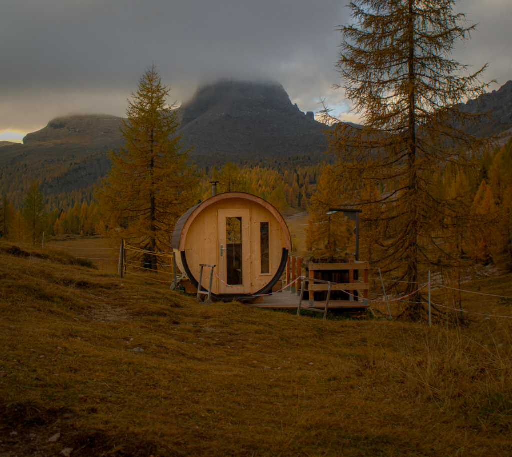 A Sauna sitting in the middle of a grassland next to Croda Da Lago/G Palmeri Rifugio
