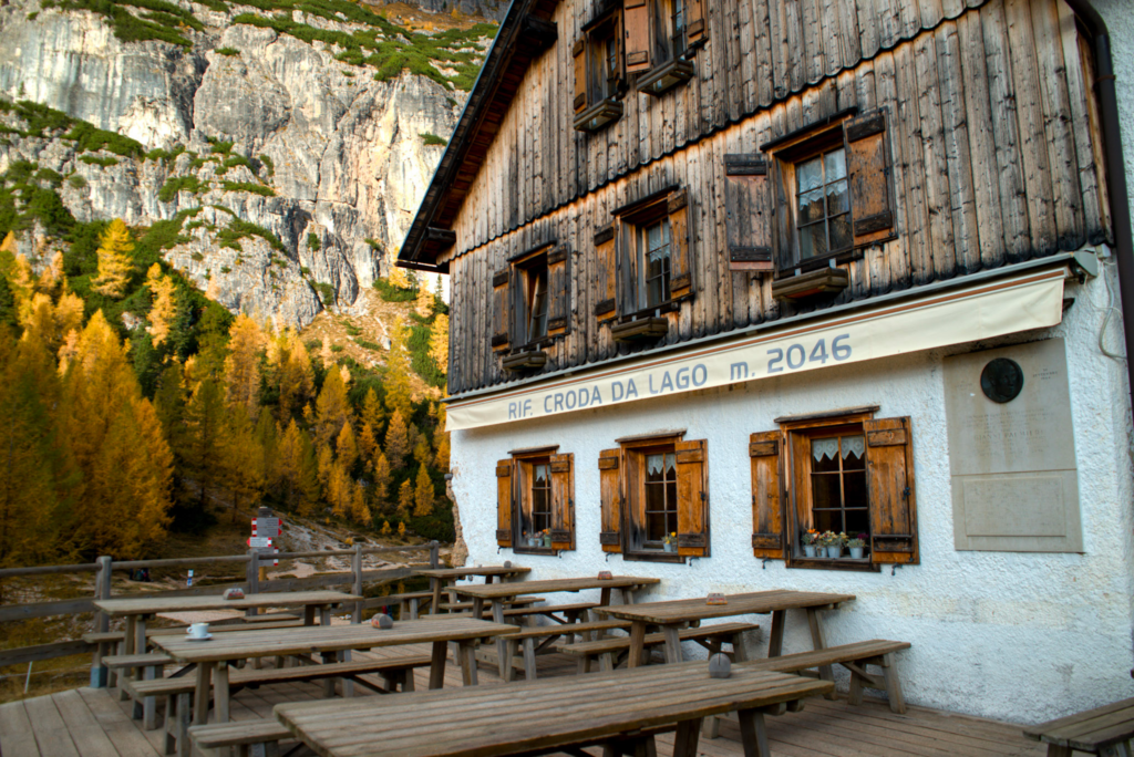 The Front of a Rifugio in the Dolomites with the Words Rifugio Croda Da Lago/G.Palmieri with vibrant larches in the back