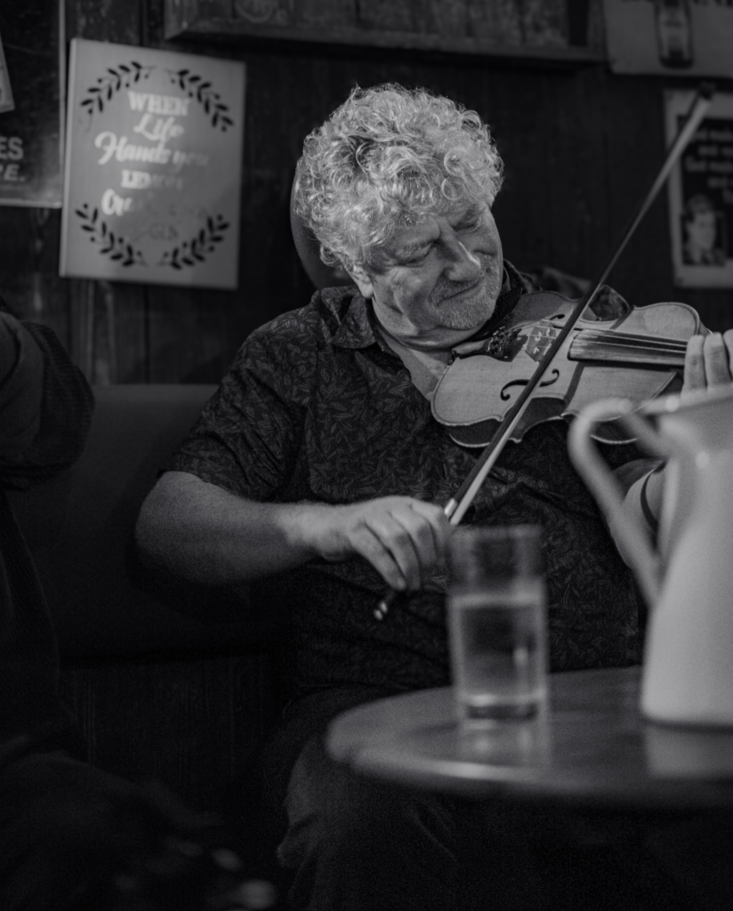 Black and White Photo of a man playing an instrument in a pub