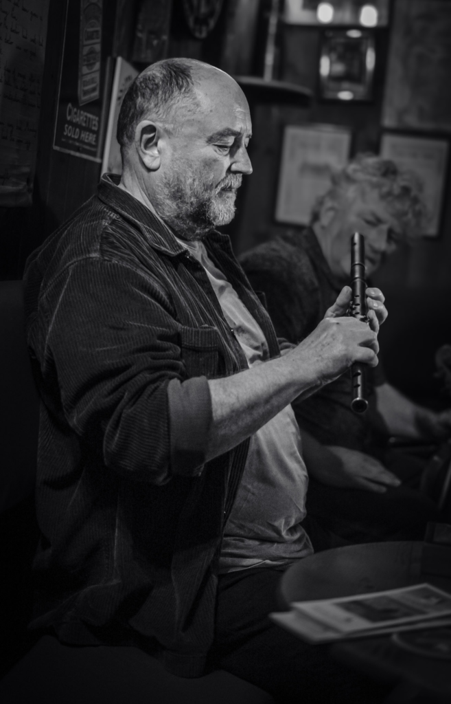 Man holding a flute explaining what his intstrument is at Olde Glen Pub in Donegal, Ireland