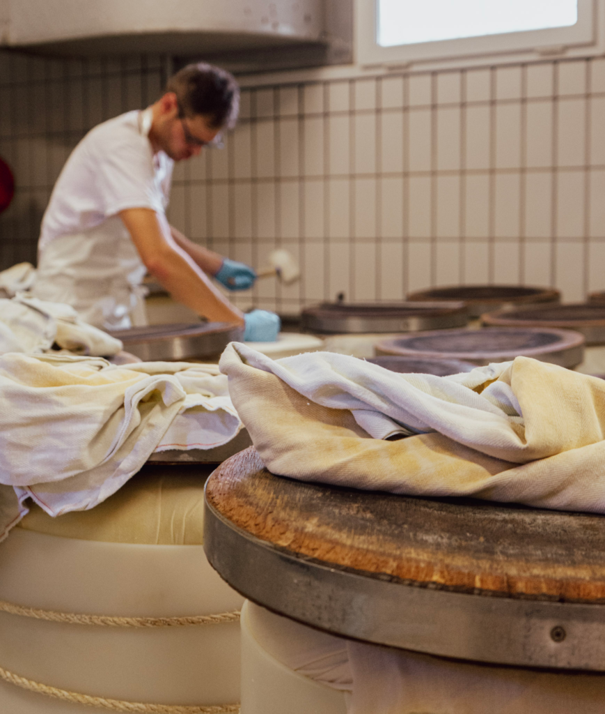 A man named eric handles a cheese mold and hammers it down to keep it in place