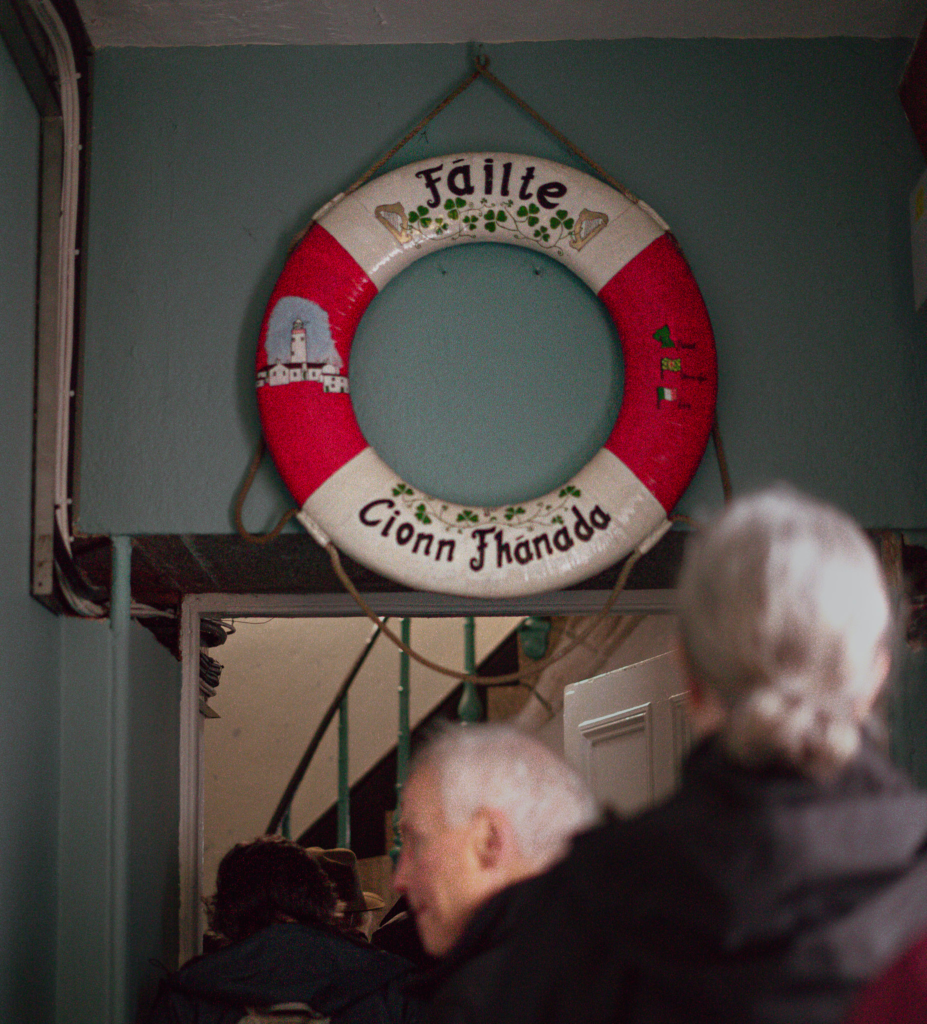 a line forming at a door with a lifesaver over it that has traditional irish writing on it