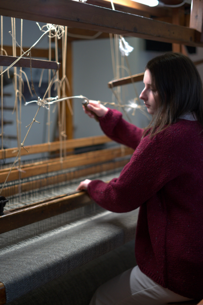 Woman with a red sweater uses loom in a shop in Donegal Town called Tirona