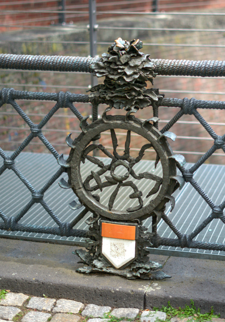 An old carriage wheel on a bridge that commemorates the city of Dusseldorf