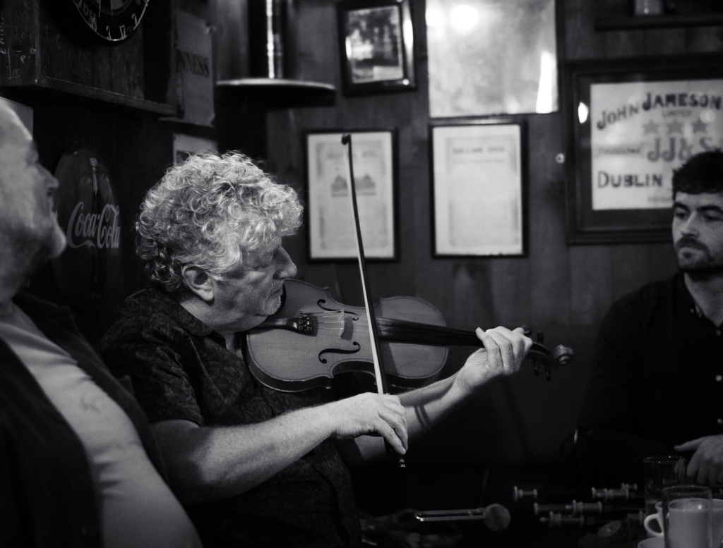 black and white photo of a man playing a fiddle in Olde Glen Pub Donegal Ireland