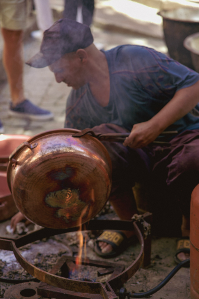 man in fes medina creates copper creations over fire