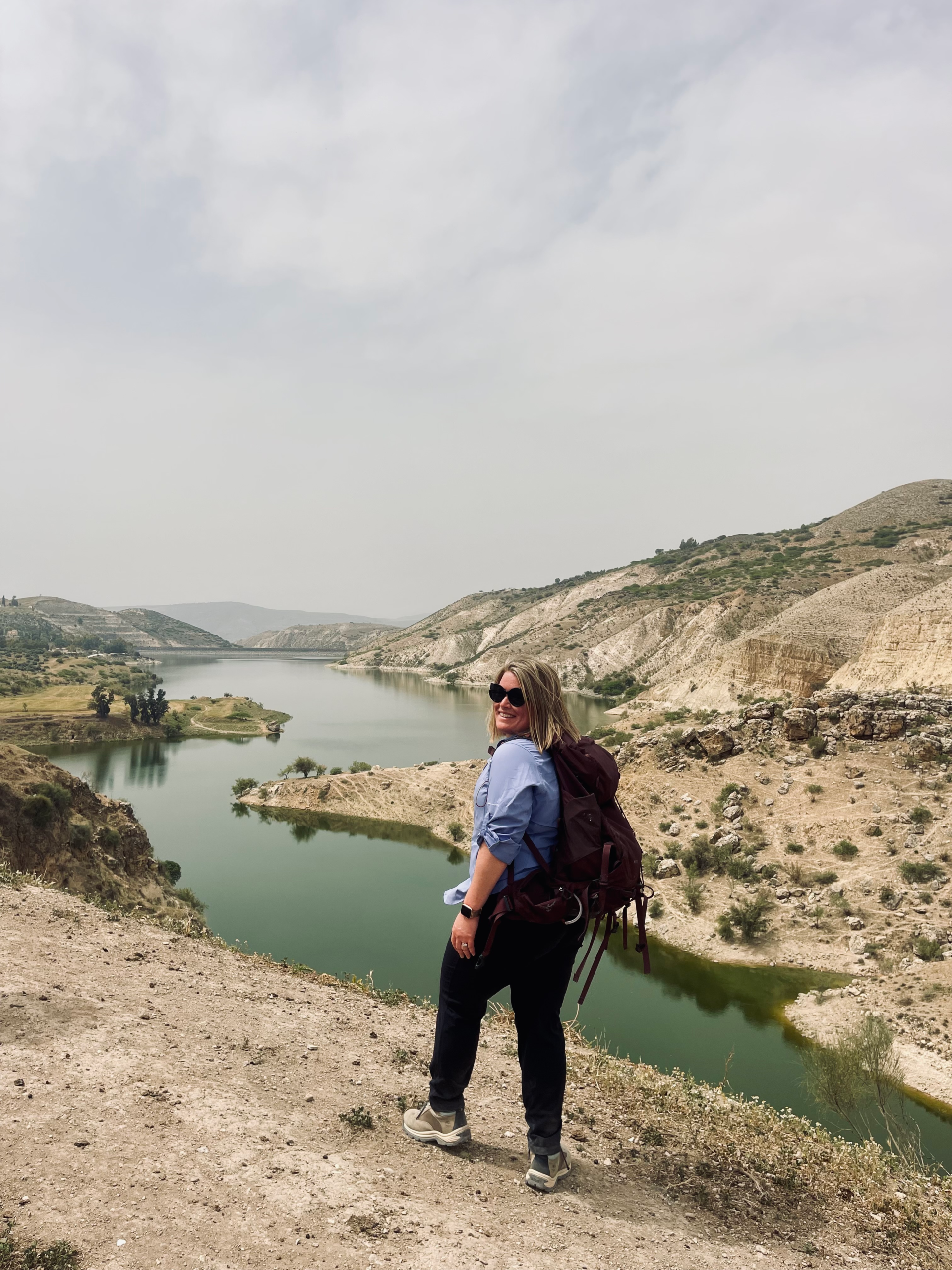Woman standing near a body of water with hiking gear on in Northern Jordan