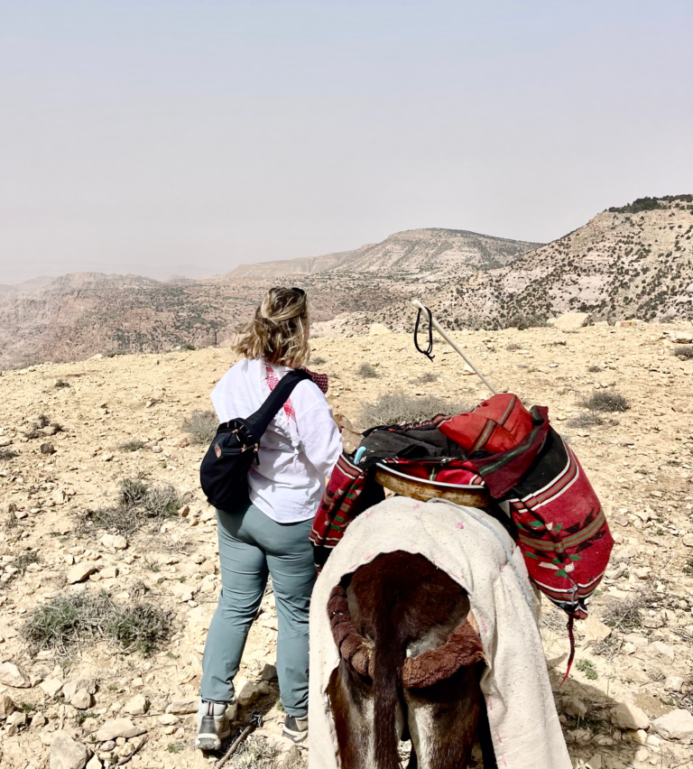 woman with pack mule standing on a cliff in Dana Biosphere Jordan