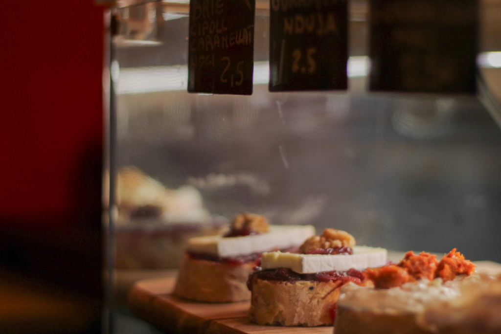 cicchetti sitting in a bar front with different toppings like anchovie, eggs and tomato sauce