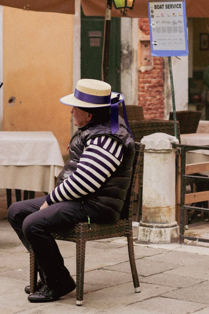 A Gondolier in his traditional outfit sitting and waiting for a customer