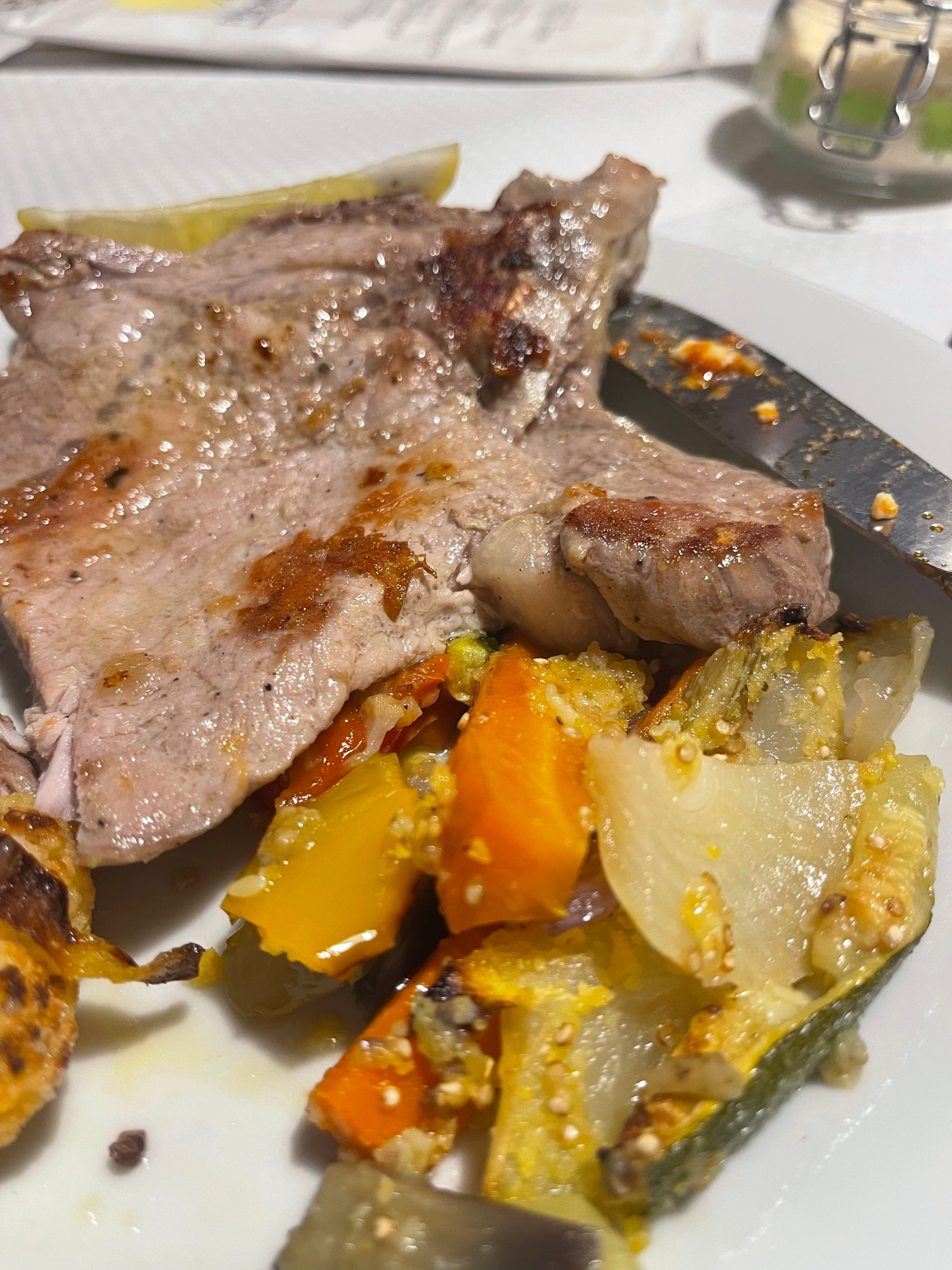 Grilled pork chop served at Rifugio Treviso, paired with a colorful medley of roasted vegetables including carrots, zucchini, onions, and bell peppers, all lightly seasoned and drizzled with olive oil.