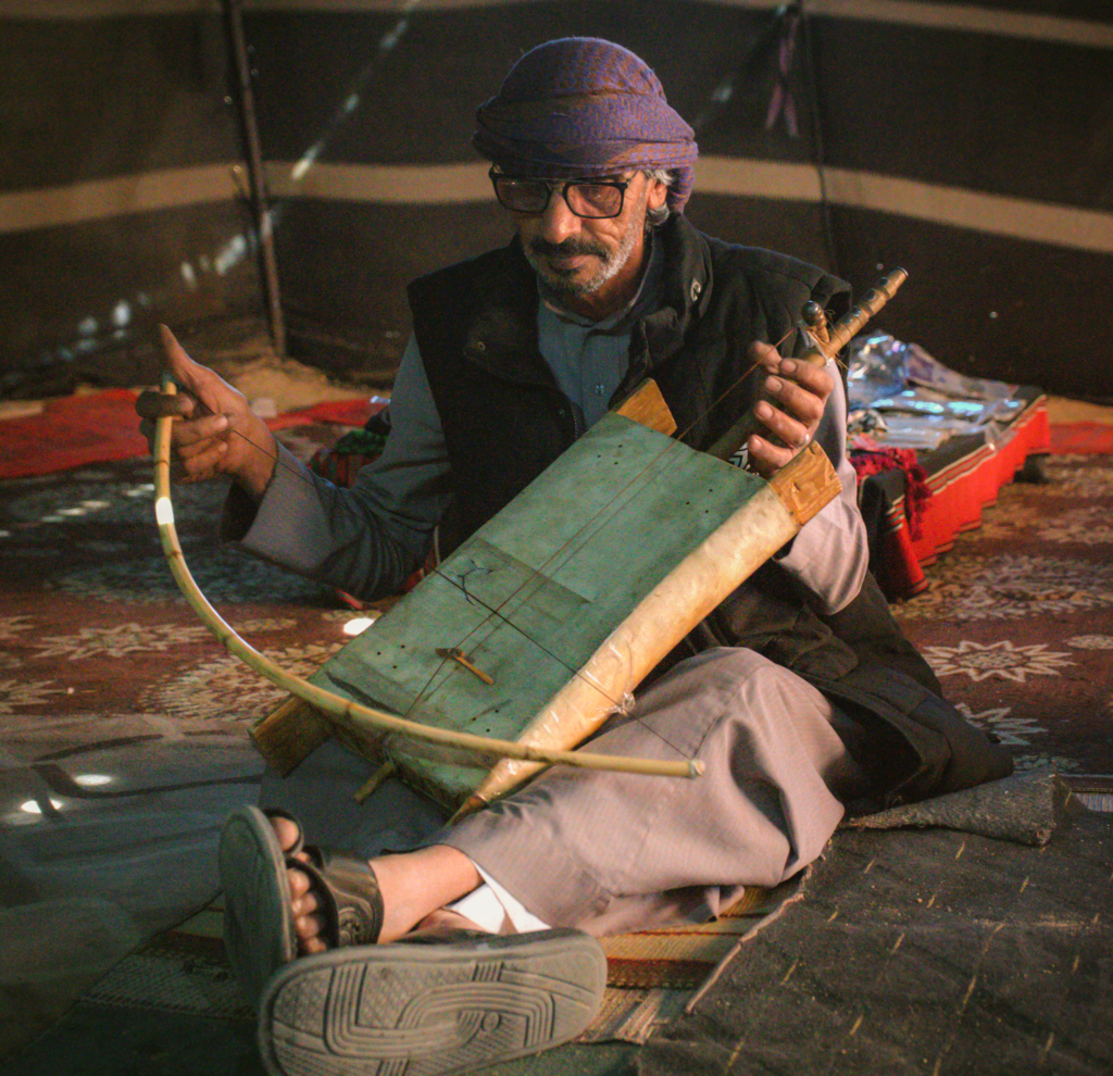 man playing a rababa in a bedouin tent