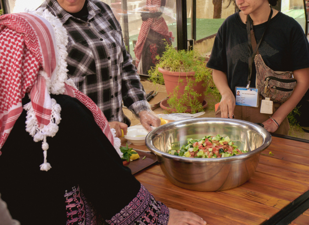 A bowl filled with salad and two women standing near it by a wooden table