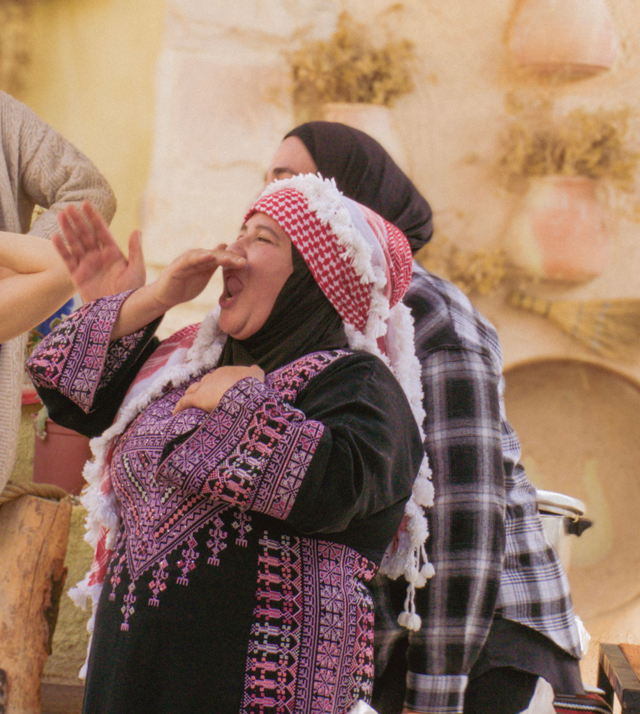 A Woman in traditional jordanian clothing singing at a cooking class in Jordan at Beit Khayrat Souf
