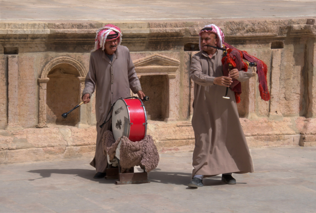 two performers at the historical site of Jerash one is holding a bagpipe and one is holding a drum