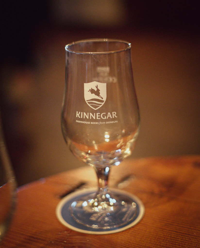 a glass sitting on a wooden table that says Kinnegar
