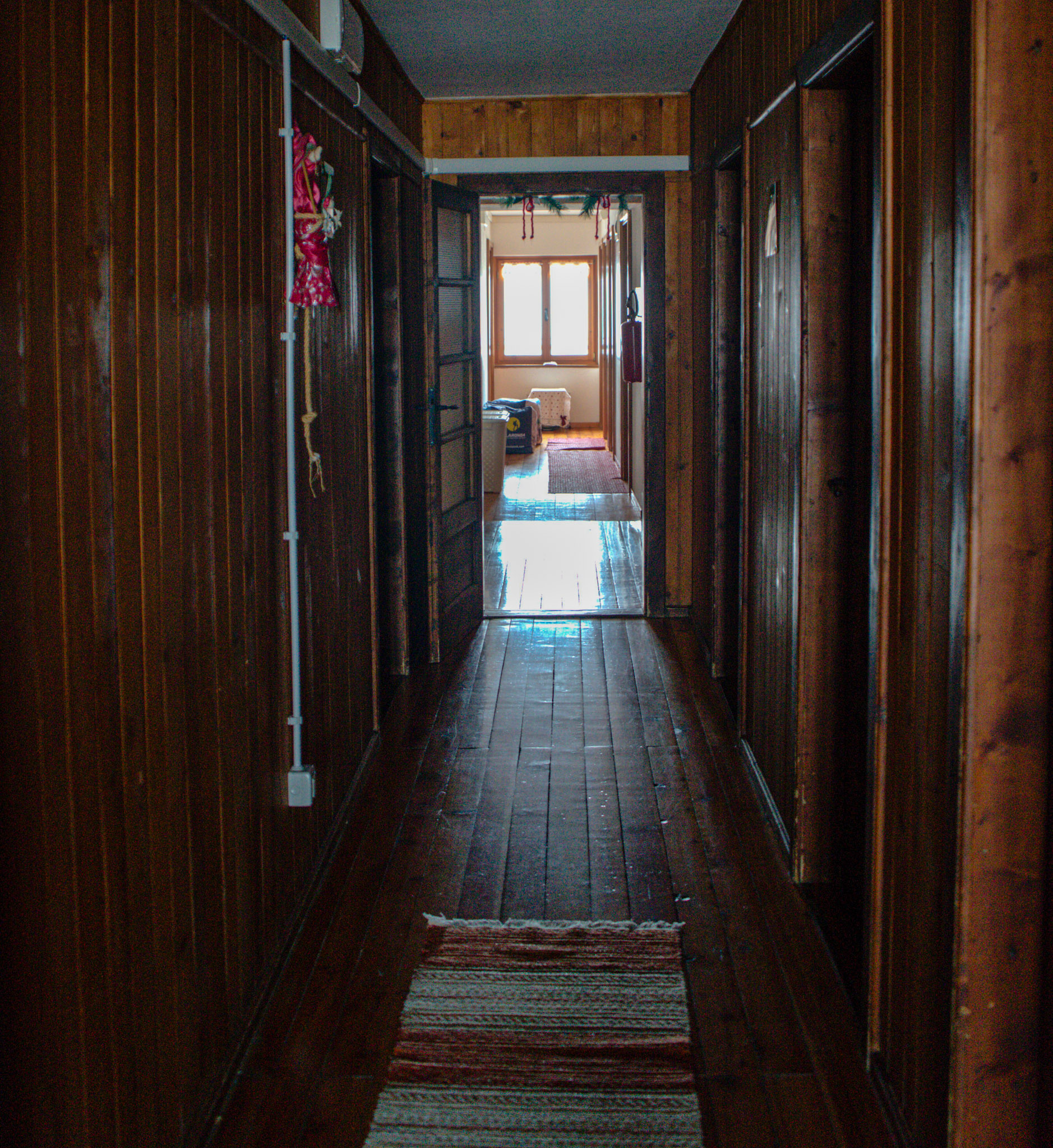 the inside of rifugio rosetta with dark wood walls and a window at the end of the hallway