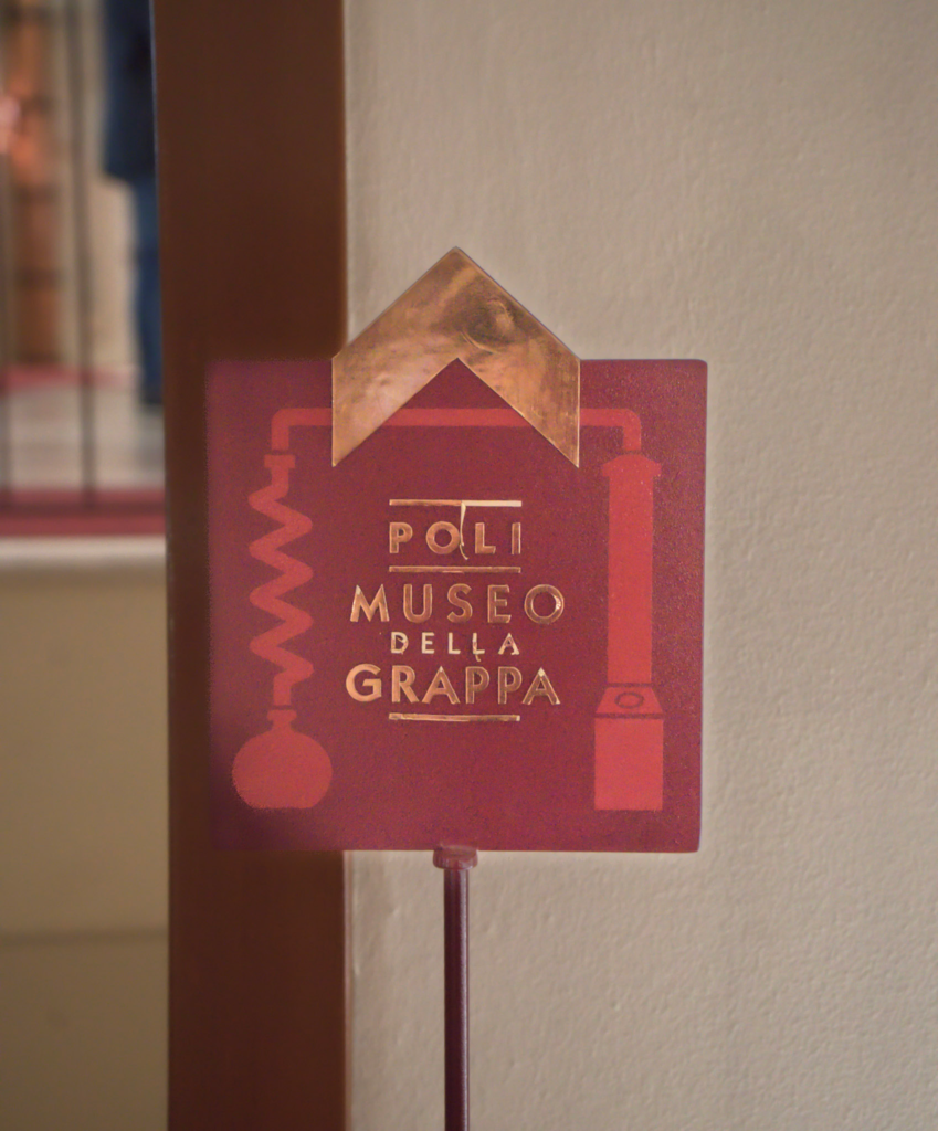 A Sign that says Poli Grappa Museum and Shop in red and gold