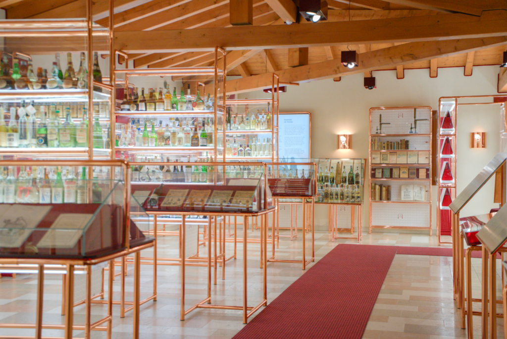 Poli grappa museum with clear cases and bottles lining shelves and a red carpet along the floor