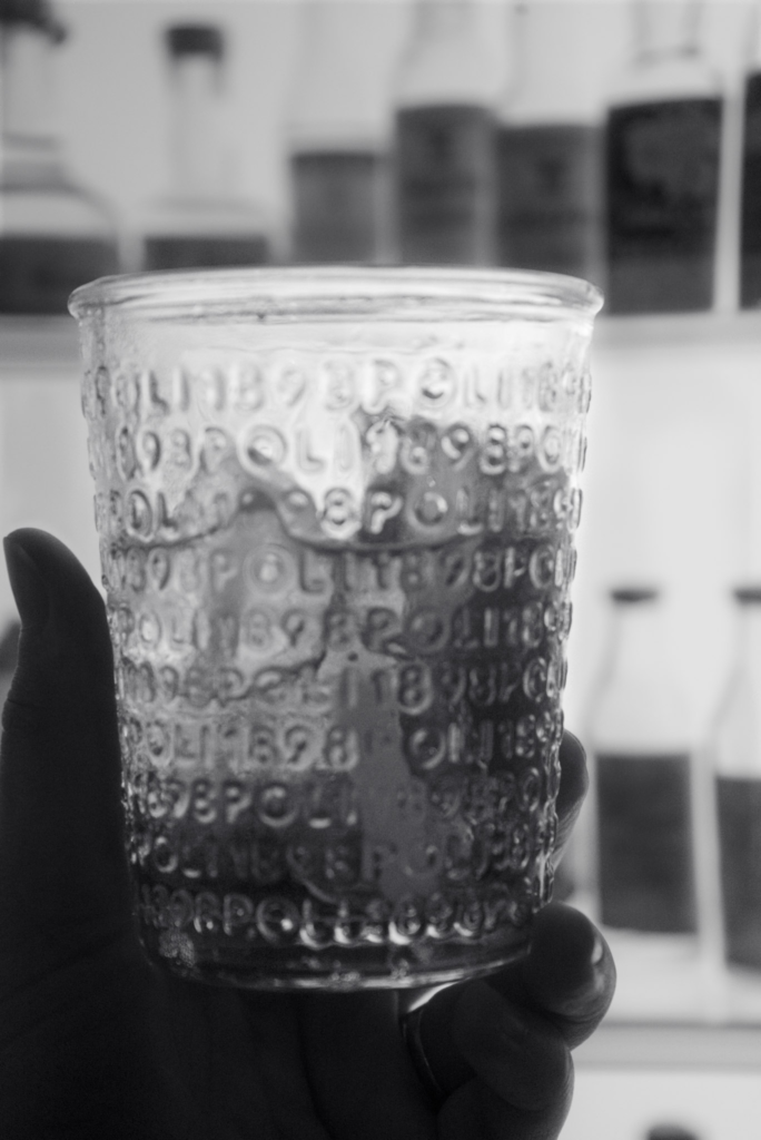 Black and white photo of A glass of Marconi 21 Gin with the words Poli Grappa on it all over the cup