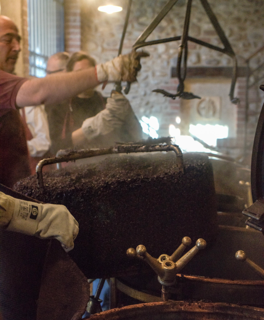 Grape skins being lifted out of a vat and being carried over to a processing unit with several people helping