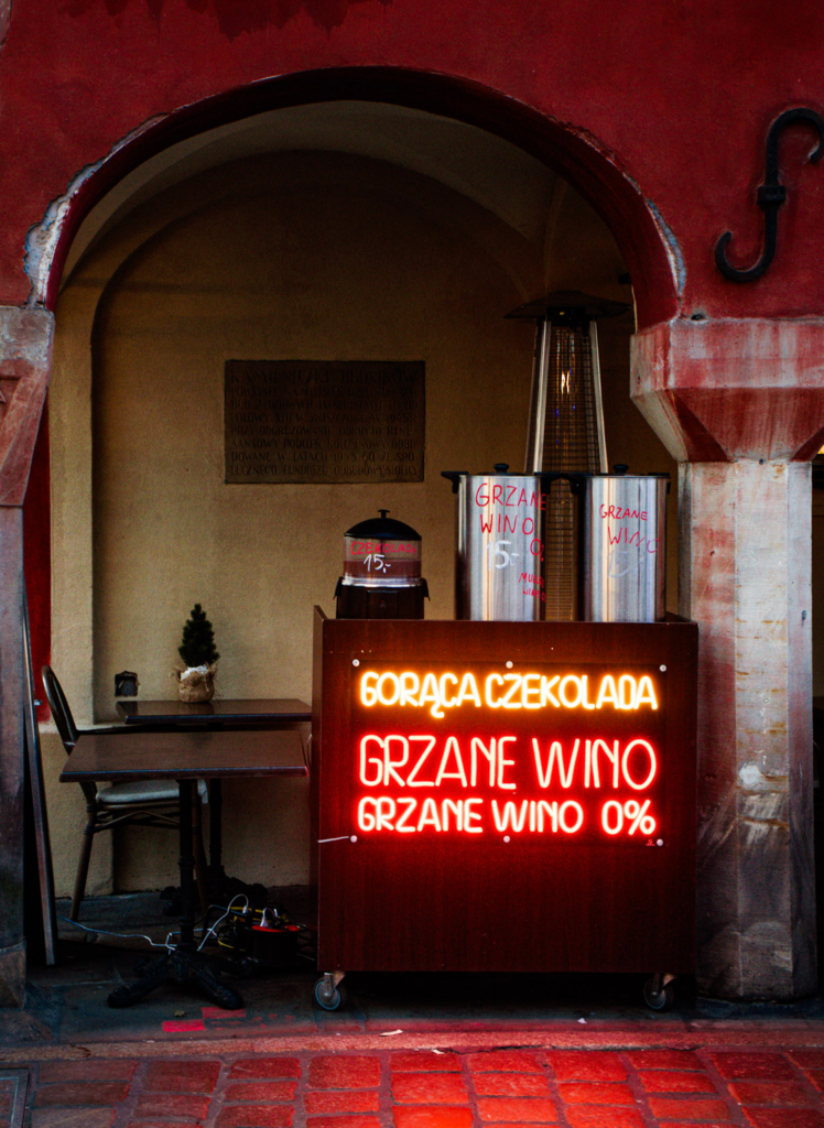a dimly lit photo with a bright sign that says wino graniec and piwo "wine, mulled wine and beer"