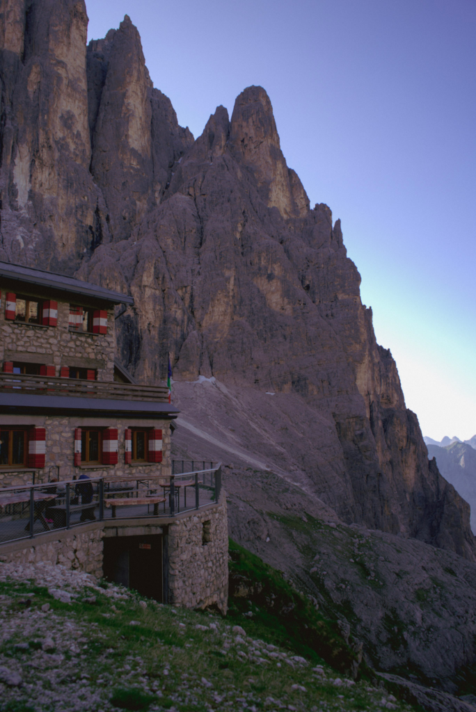 Rifugio Pradidali in the morning light with the Cima Canali behind it the red shutters stand out against the dark facade