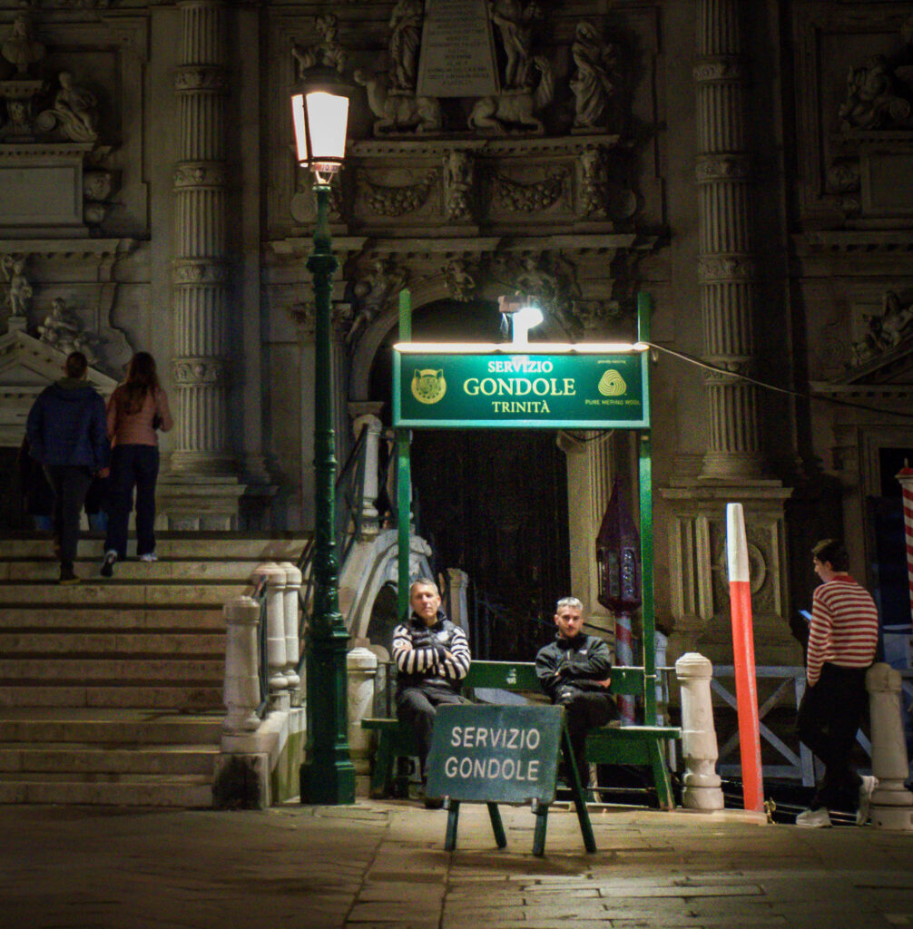 three gondoliers wait on customers at a gondolier stop in the trinity area of Venice