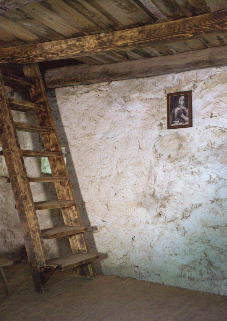 a set of wooden stairs set against a stone wall in Theth Albania at the Reconciliation tower